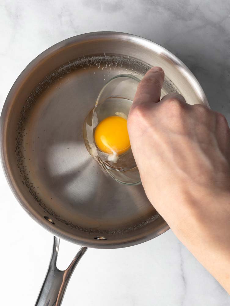 egg being dropped into a pot with hot water