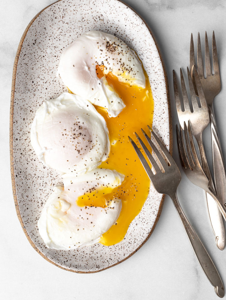 three poached egg on a plate with egg yolks oozing out