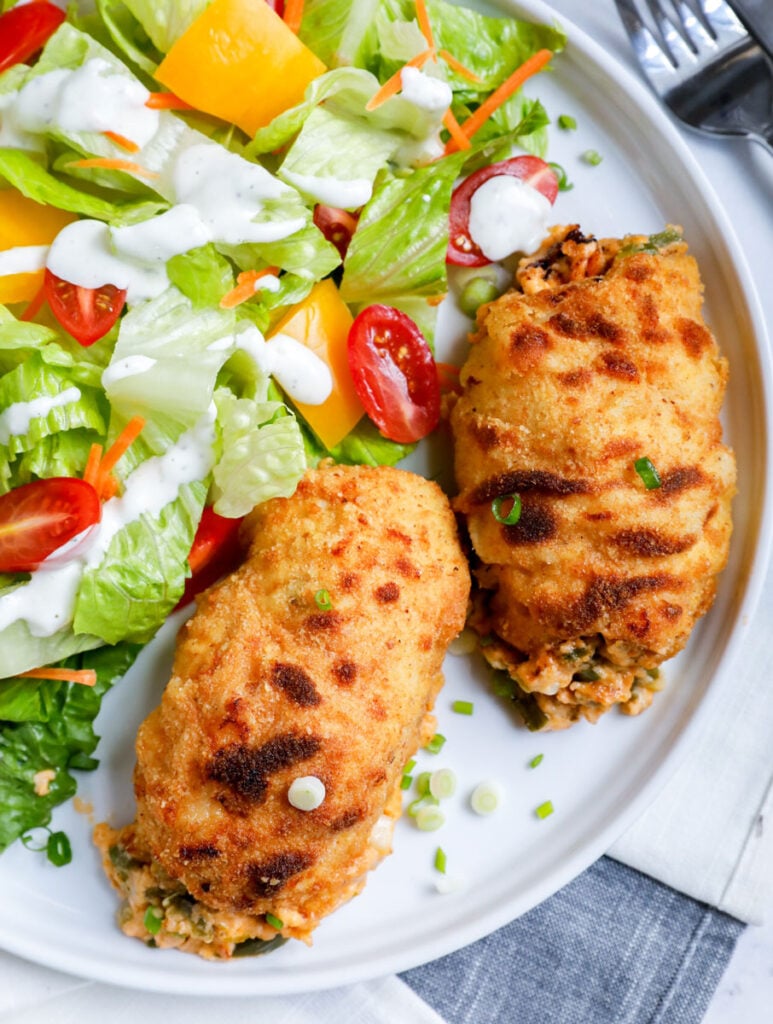 Top down shot of stuffed chicken with salad.