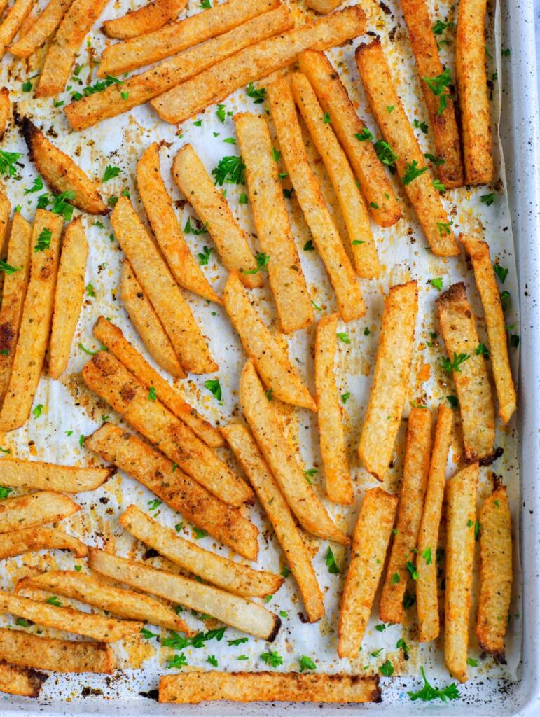 Top down shot of baked jicama fries on a baking sheet.