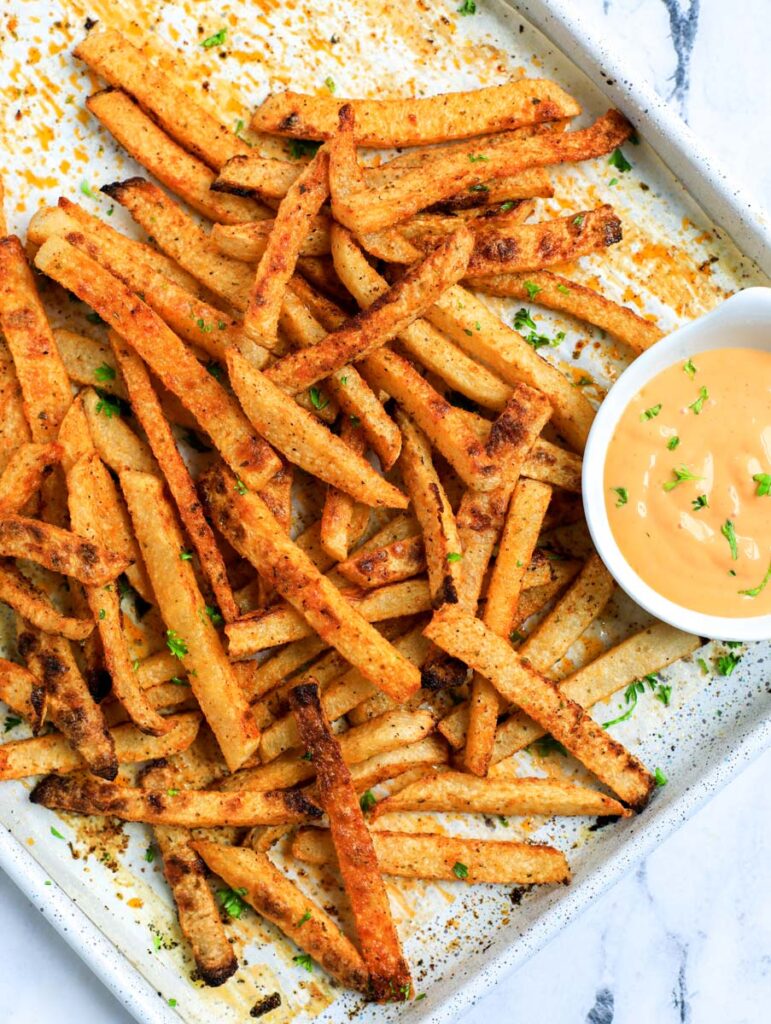 Baked jicama fries on a baking tray with dip