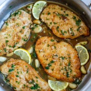 Top down shot of lemon and chicken in a skillet.