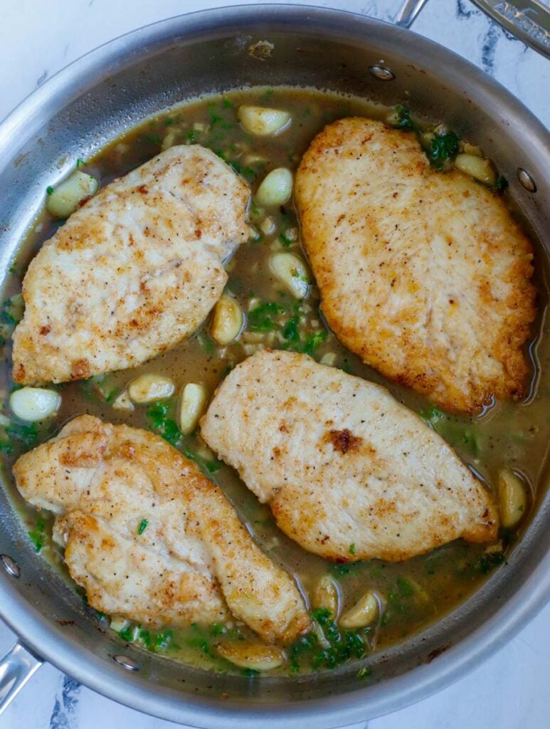 Top down view of chicken with sauce in a skillet.