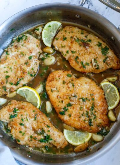Top down shot of lemon and chicken in a skillet.