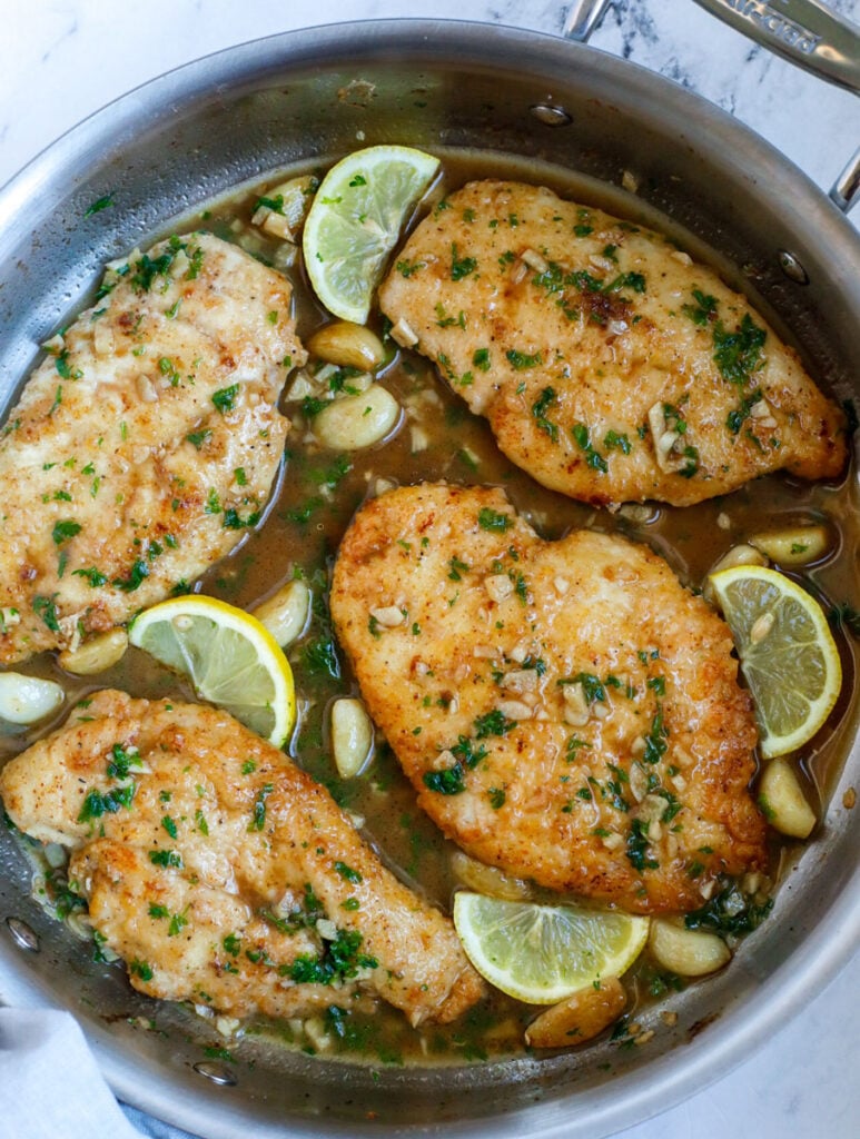 Top down shot of lemon and chicken in a skillet.