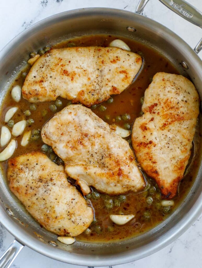 Lemon chicken piccata in a pan.