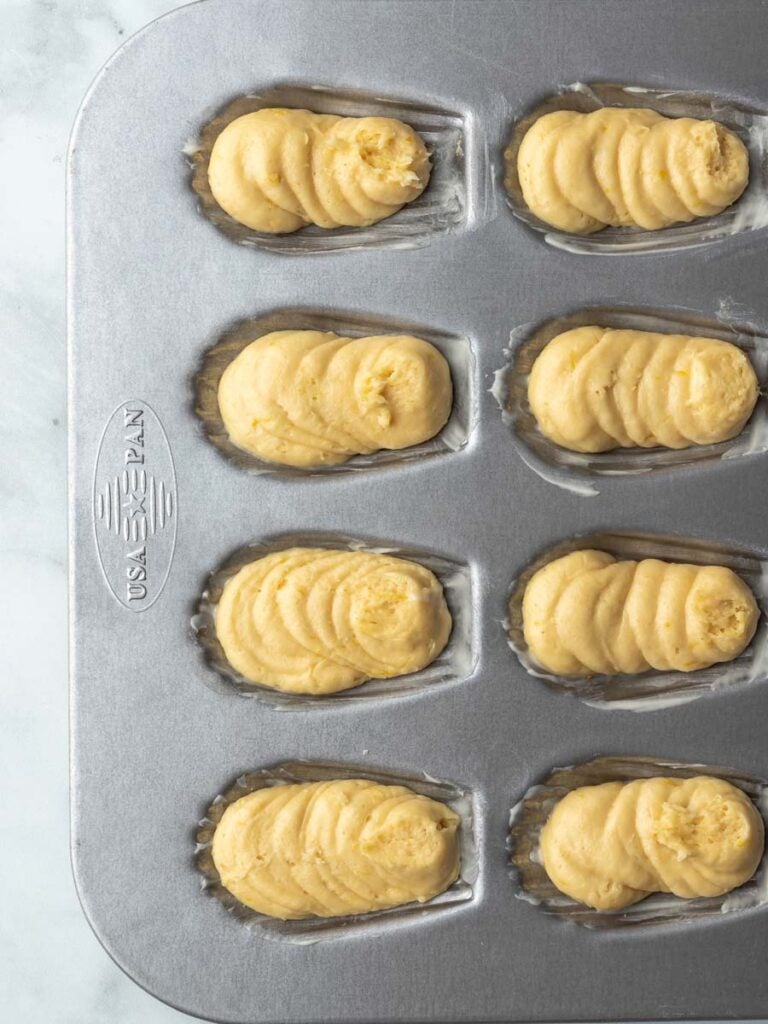 Lemon madeleines batter inside of a pan.