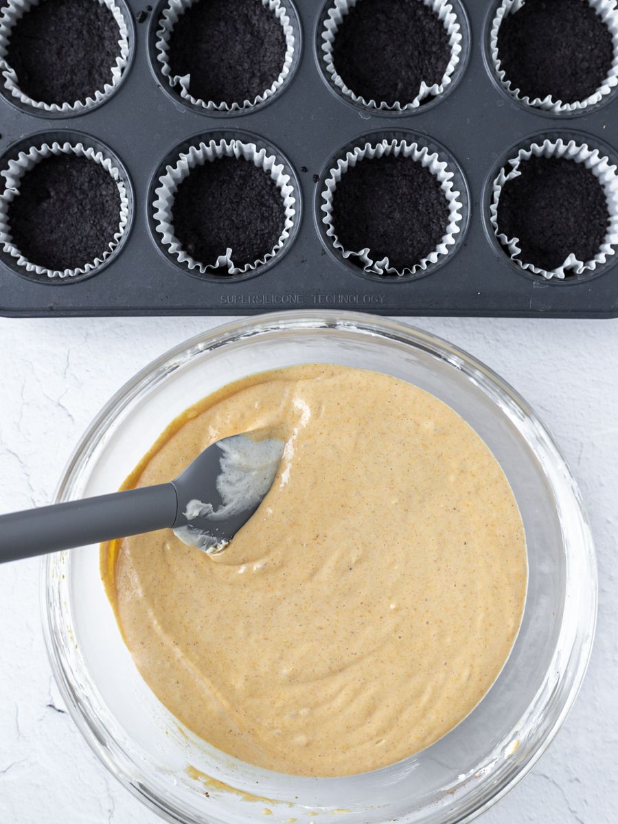 Overhead shot of filling mixture in a bowl and oreo base in molds.