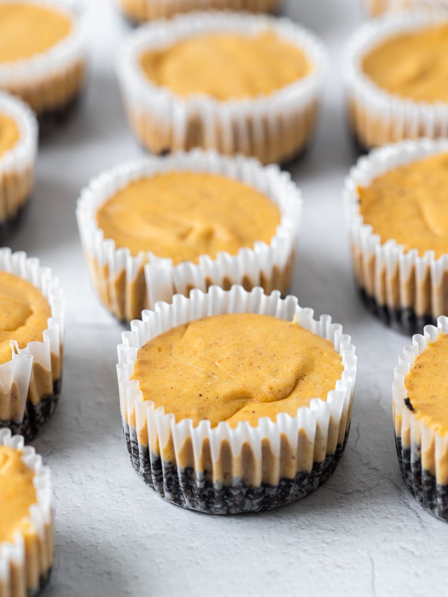 Mini pumpkin cheesecakes on a white surface.