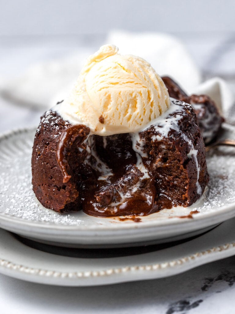 A lava cake cut opened with a scoop of ice cream on top.