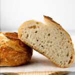 Half of a loaf of bread, cut, leaned overtop the other half of the bread.