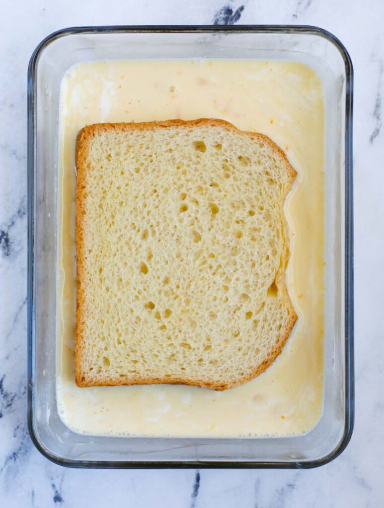 Soaking a slice of bread in the custard.