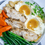 plate of oven baked turkey with mashed potatoes, gravy, and vegetables