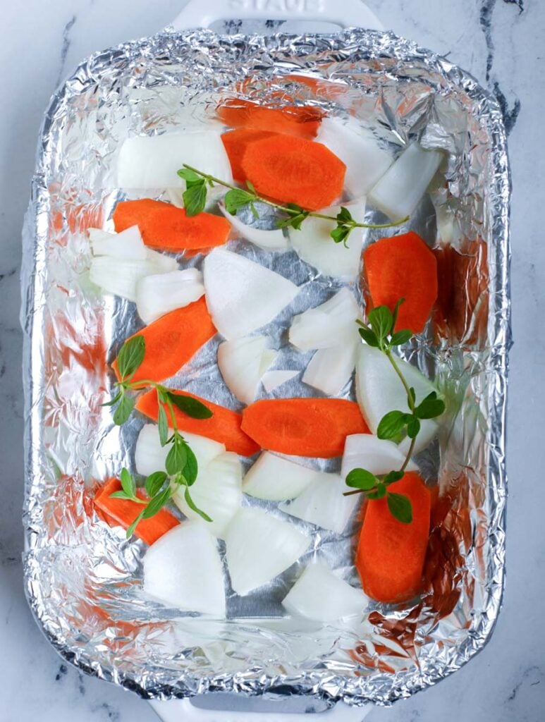 Add in the onions, oregano and carrots in a tin foil lined pan