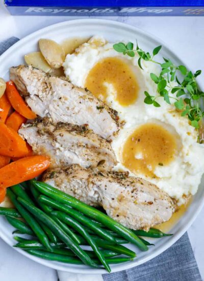 plate of oven baked turkey with mashed potatoes, gravy, and vegetables