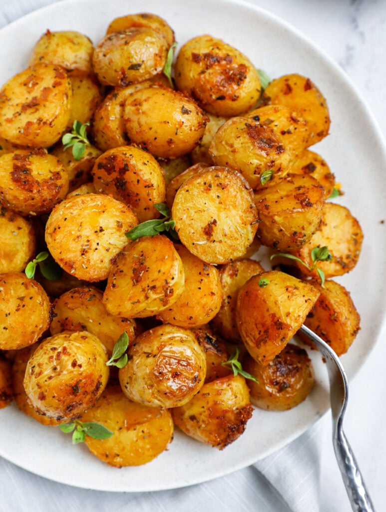 Top down shot of oven roasted potatoes on a white dish.