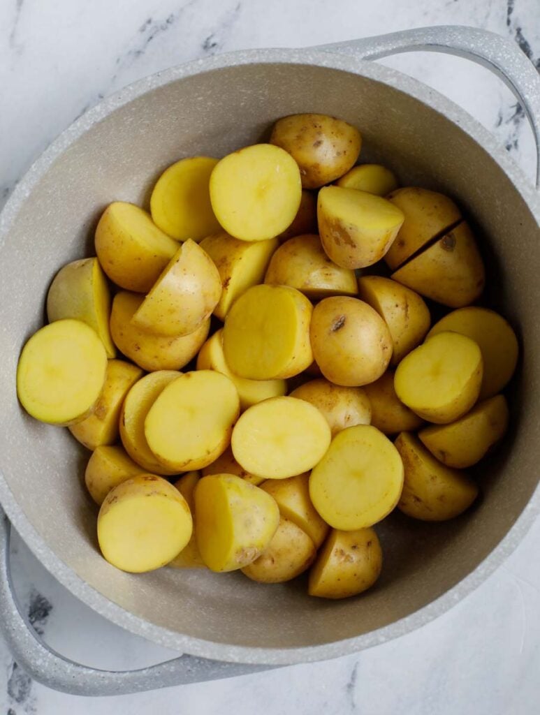 Top down shot of uncooked potatoes in a white bowl.