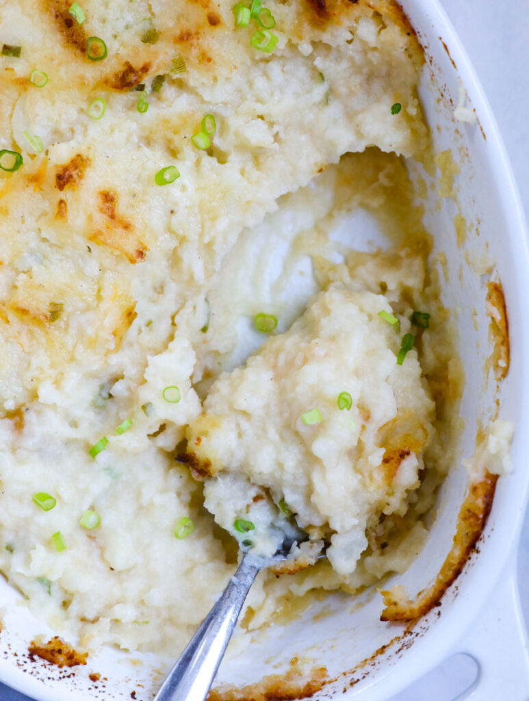 Top down view of mashed potatoes in a baking dish with a portion taken out. 