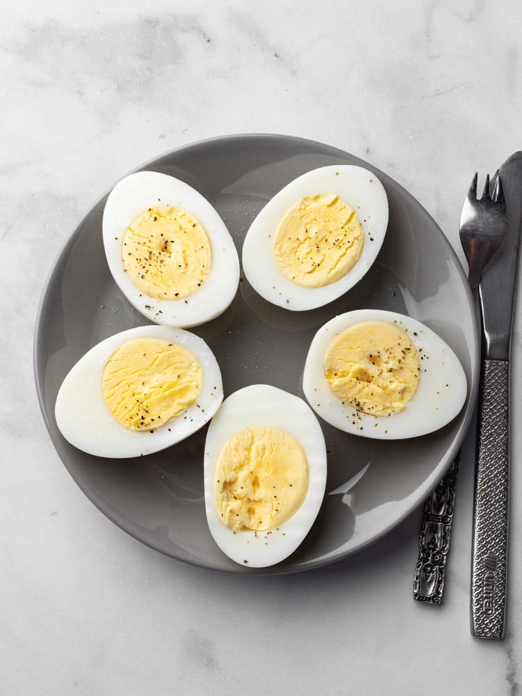 hard boiled eggs sliced through showing the yolk and seasoned with pepper