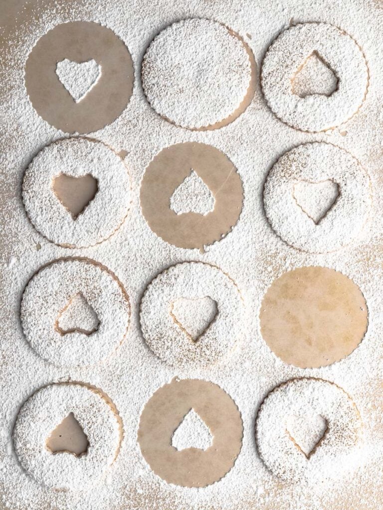 Dusting baked linzer cookies with icing sugar.