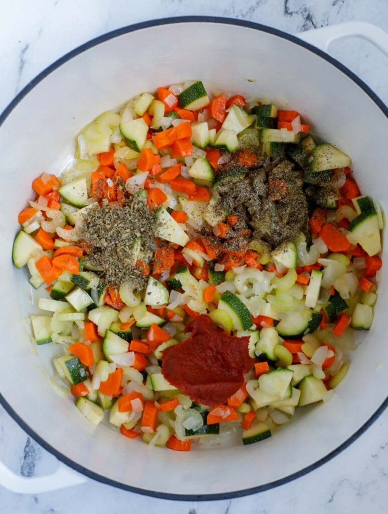 Vegetables, seasoning and tomato paste in a bowl.