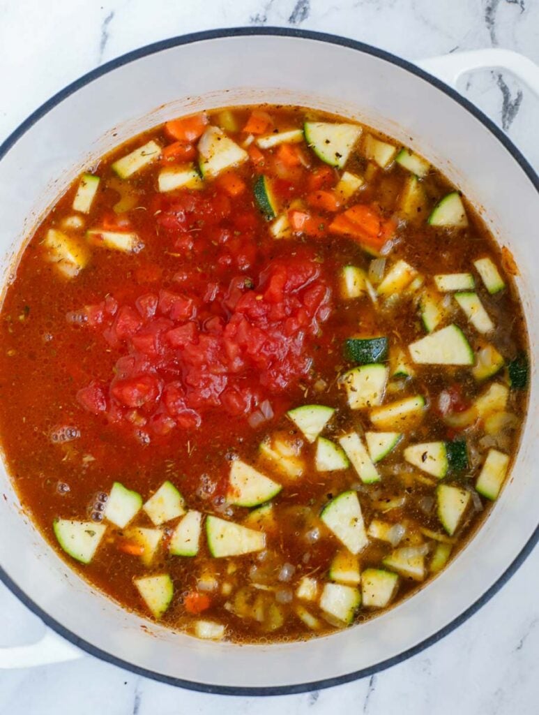 Broth, vegetables and tomato paste in a pot.