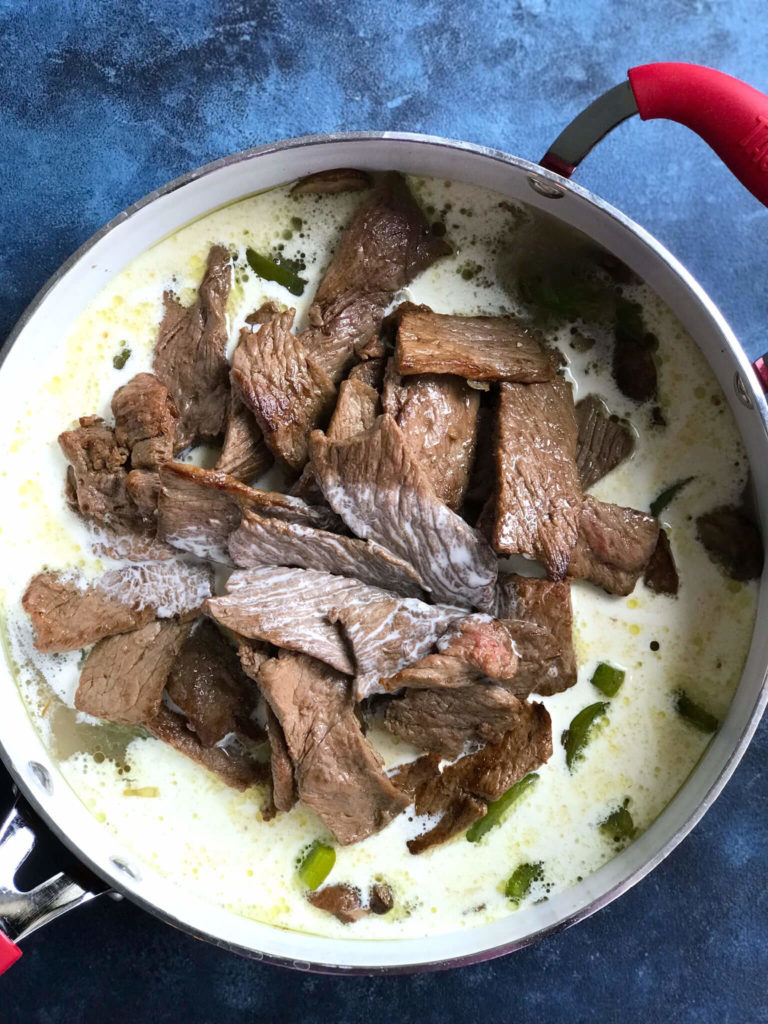 Adding cream to the skillet with the meat and veggies