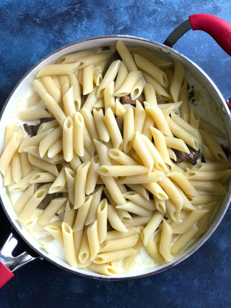 One Pot Philly Cheese Steak Pasta - cooked pasta in the skillet with the cream and steak 