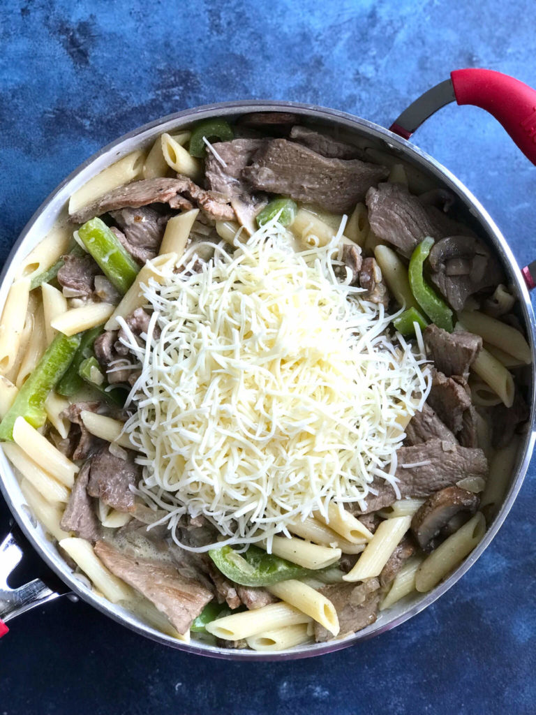 Shredded cheese on top of the steak, pasta, veggies and cream