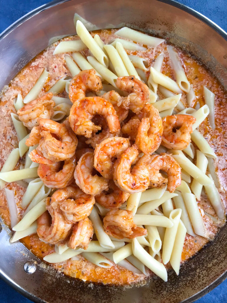 Cooking Creamy Shrimp Penne Pasta With Red Pepper Sauce in a skillet