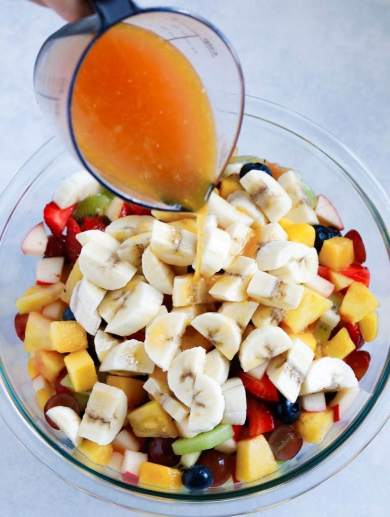 Dressing being poured over the chopped fruits