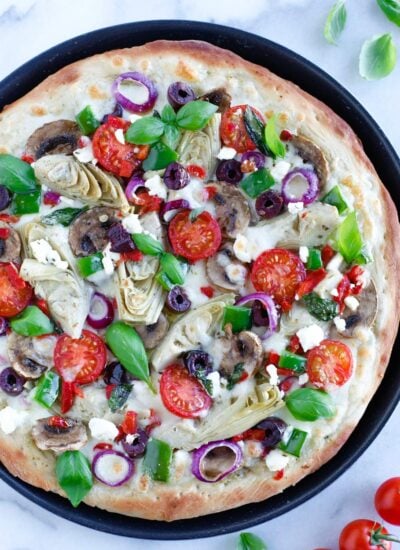 Mediterranean Veggie Pizza with delicious pesto sauce, topped with some alfredo sauce, and packed with fresh veggies and cheese.