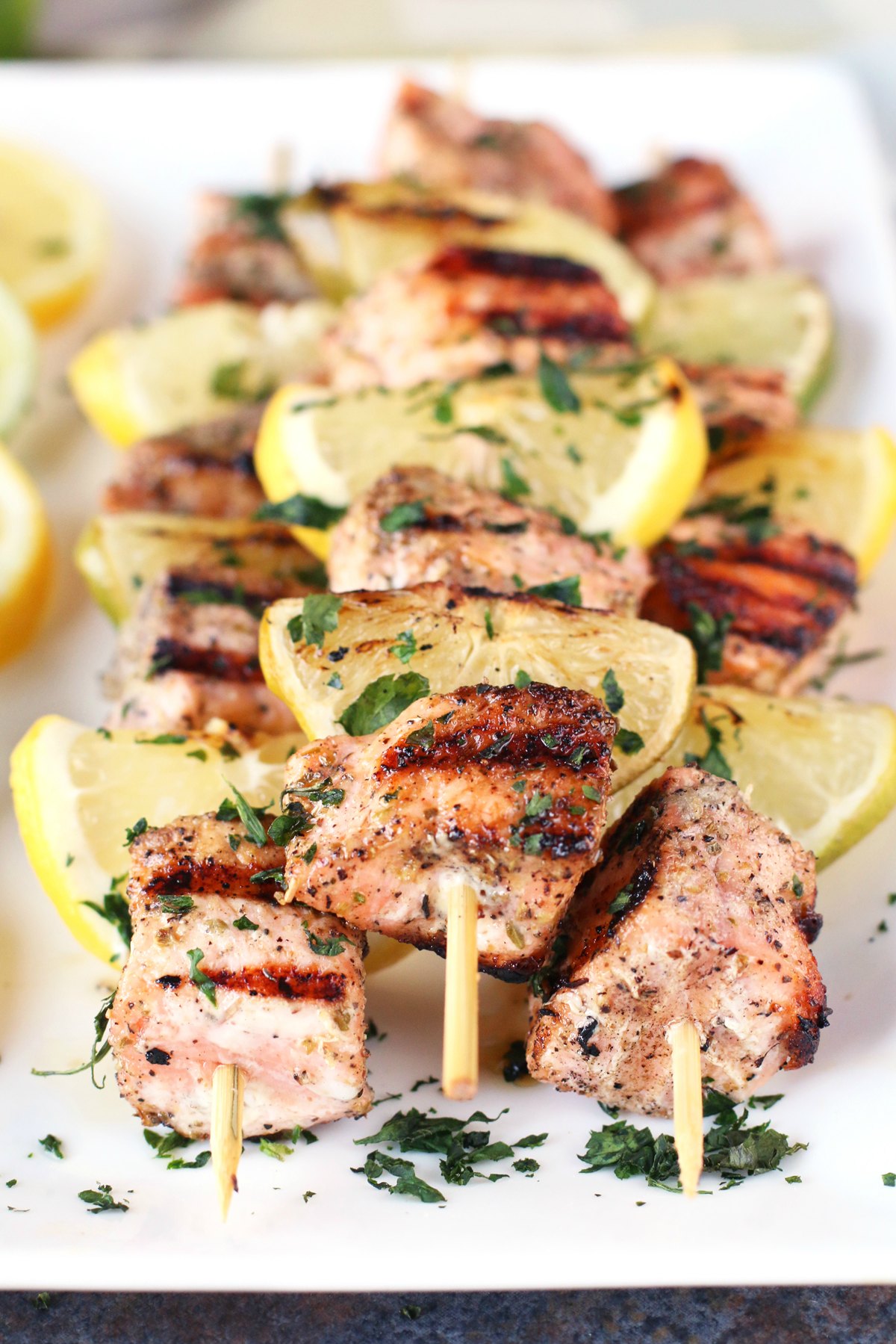 A platter of salmon skewers cooked and topped with diced parsley