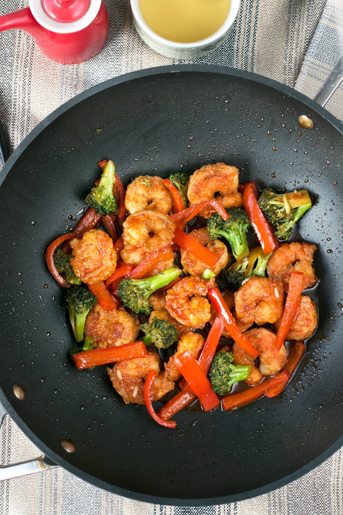 Honey sriracha shrimp peppers and broccoli being sauteed in a wok