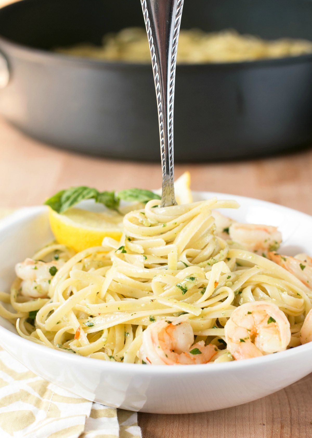 Large white bowl of pesto shrimp scampi pasta with a fork in the center