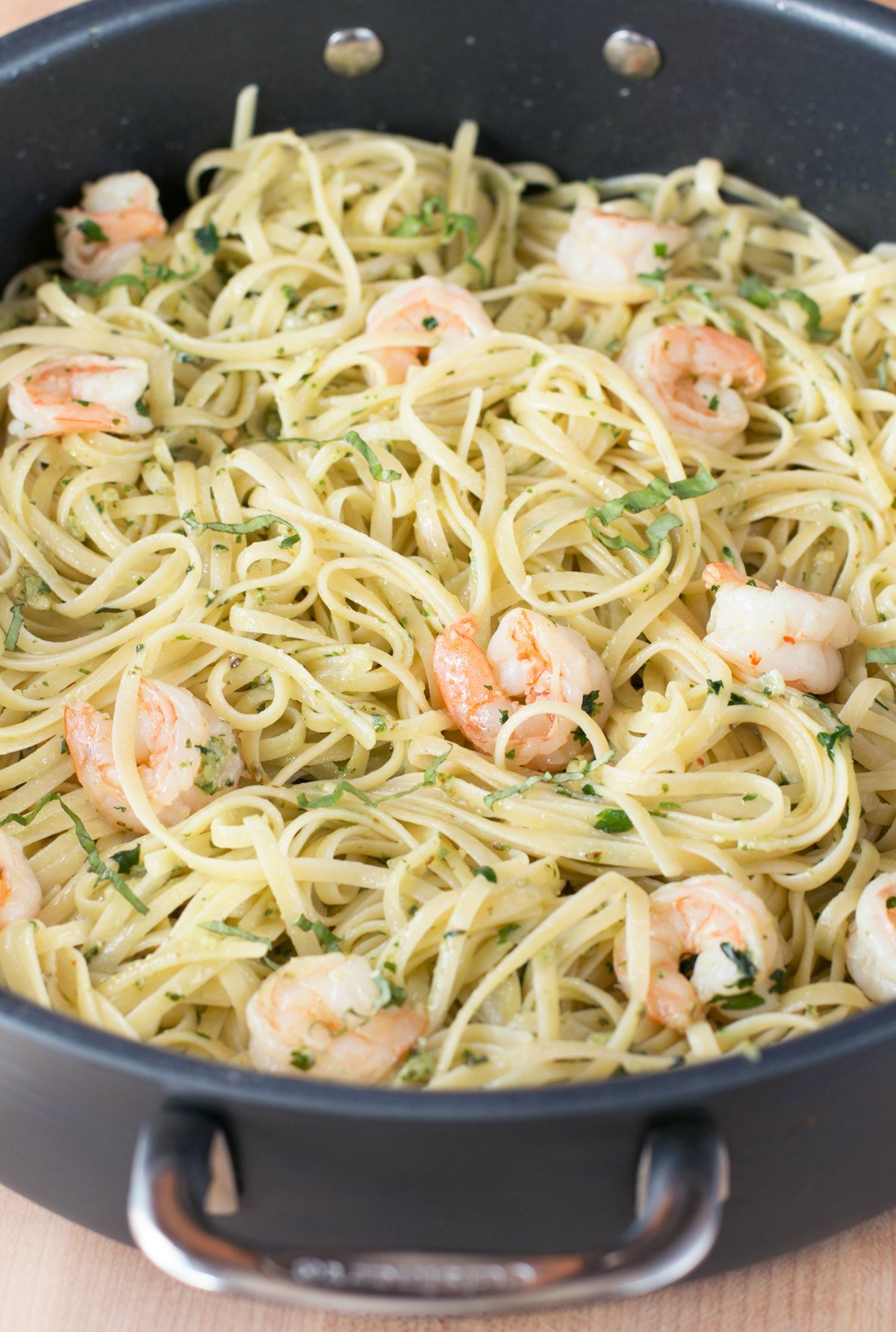 Pesto shrimp scampi with pasta being tossed together in a large stockpot