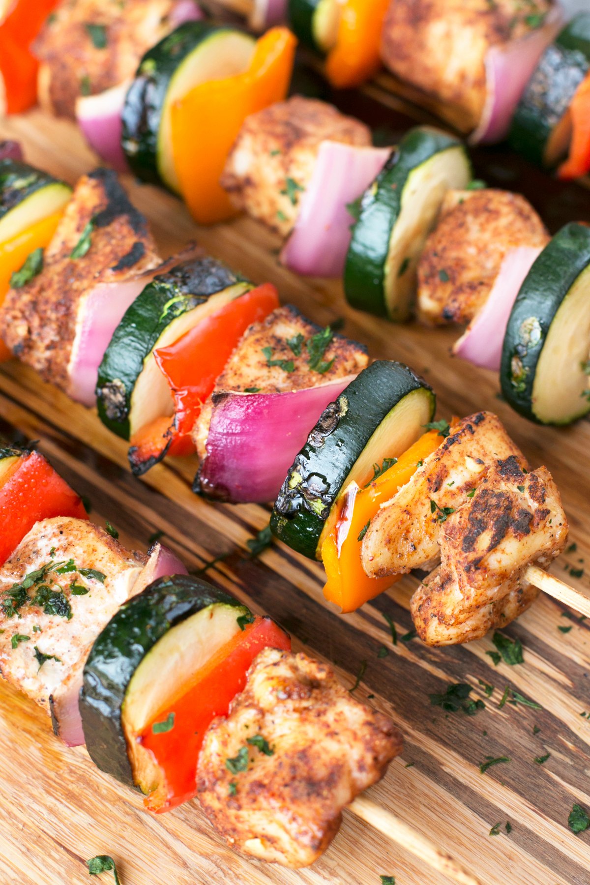 Seasoned vegetable and chicken kabobs on a wooden platter