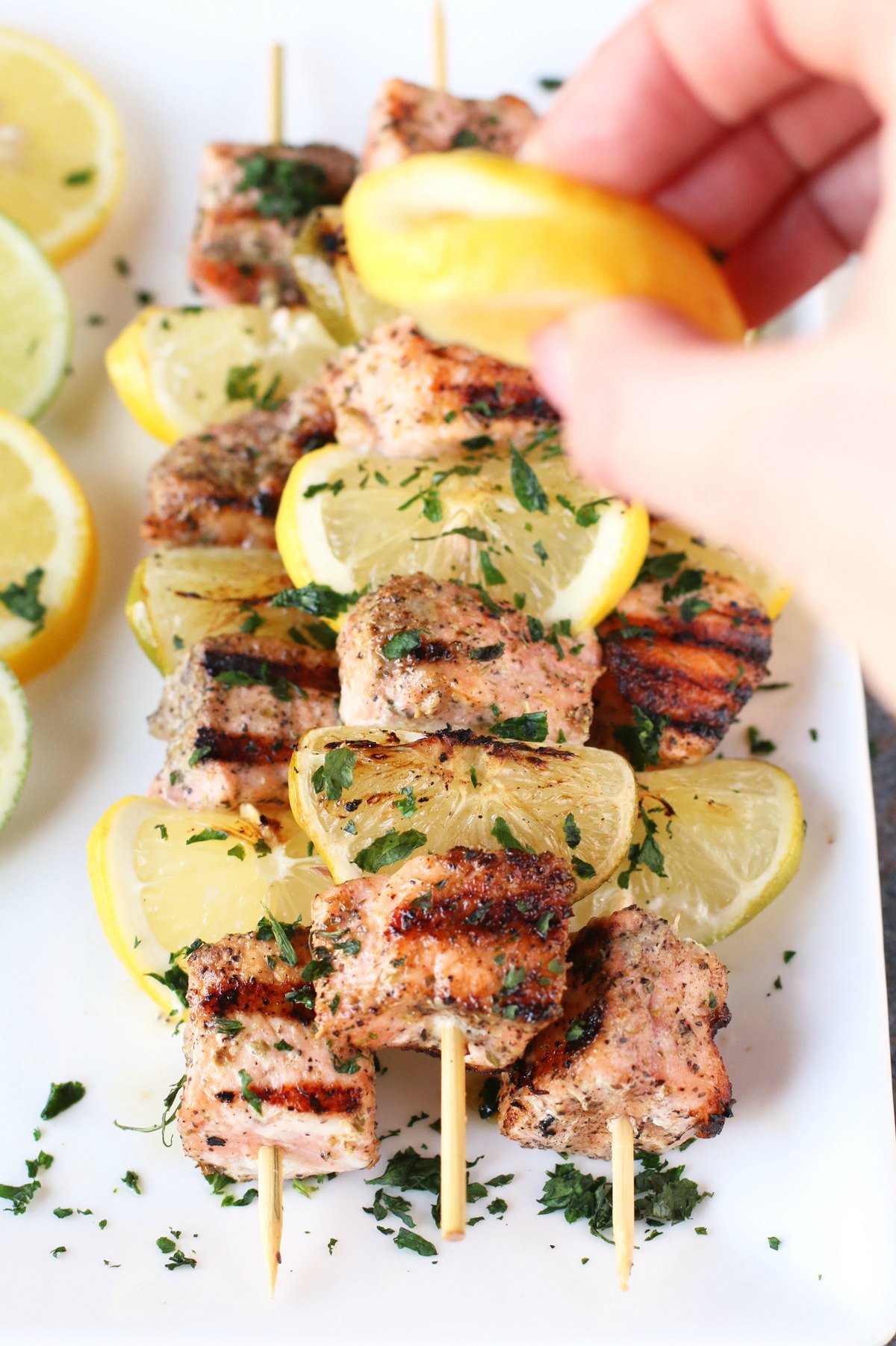 Squeezing fresh lime over grilled salmon skewers