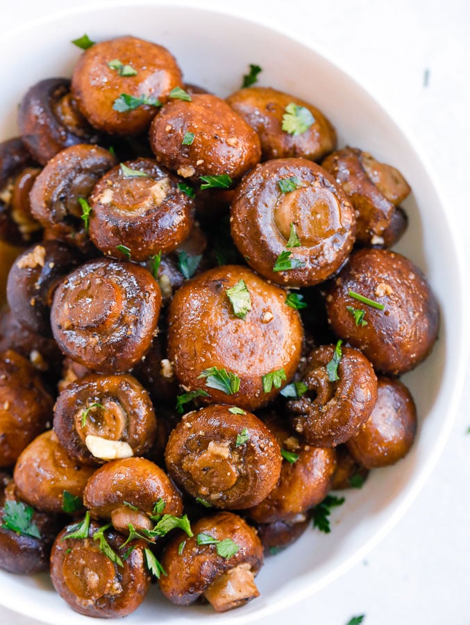 Mushrooms roasted with garlic in a white bowl. 