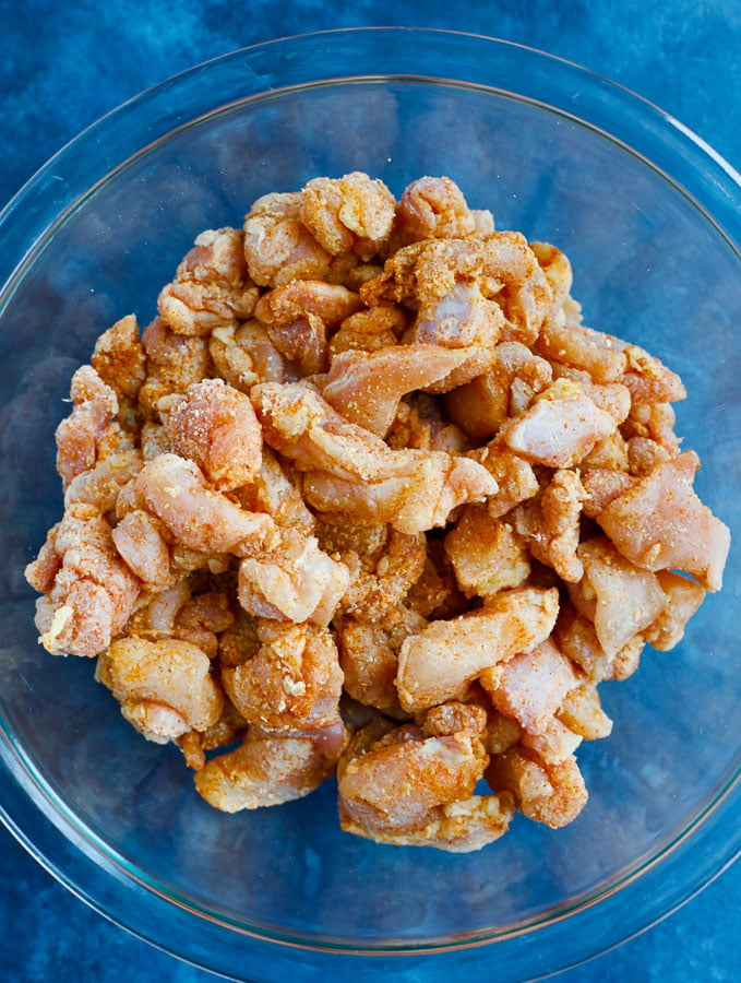 small cubed chicken in a glass bowl after being mixed with the flour and spices.