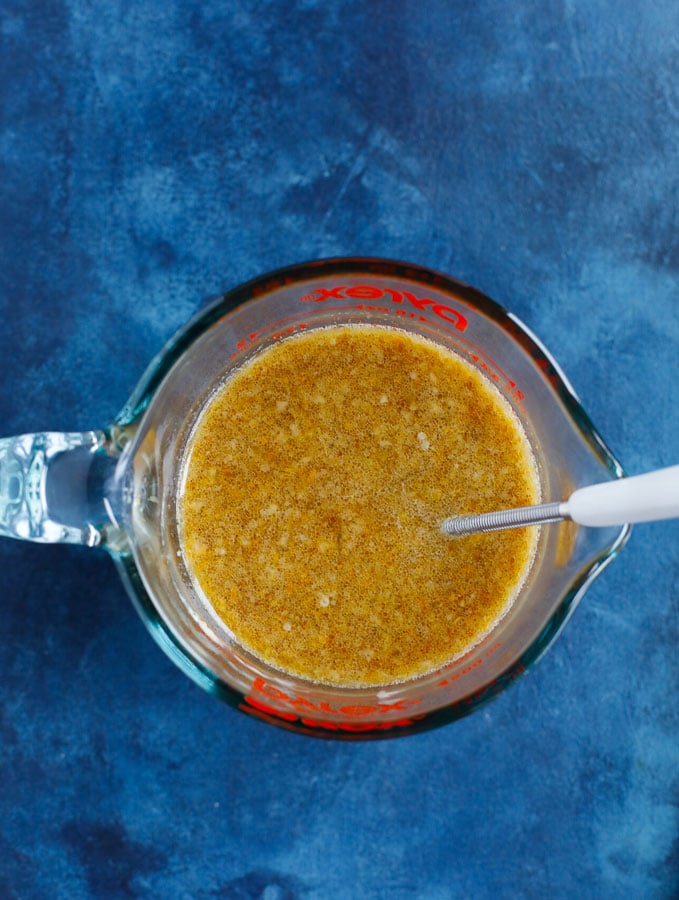 orange sauce mix in a measure cup with a whisk inside the cup.