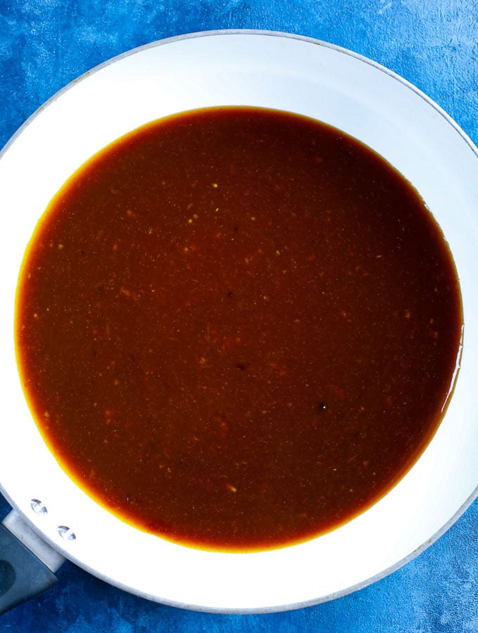 orange chicken sauce cooked in a white skillet.