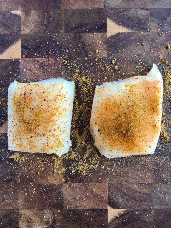 Marinated mahi mahi fillets on a wooden counter.