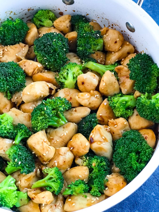 Spicy Teriyaki Chicken with Broccoli in a white skillet on a blue counter.