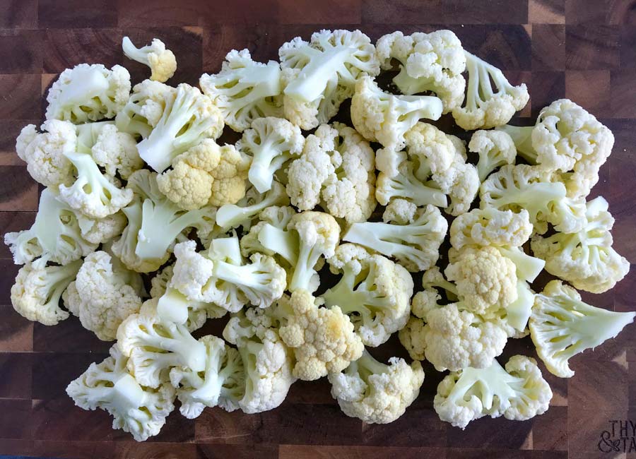 Fresh cauliflower florets cut on a wooden cutting board.