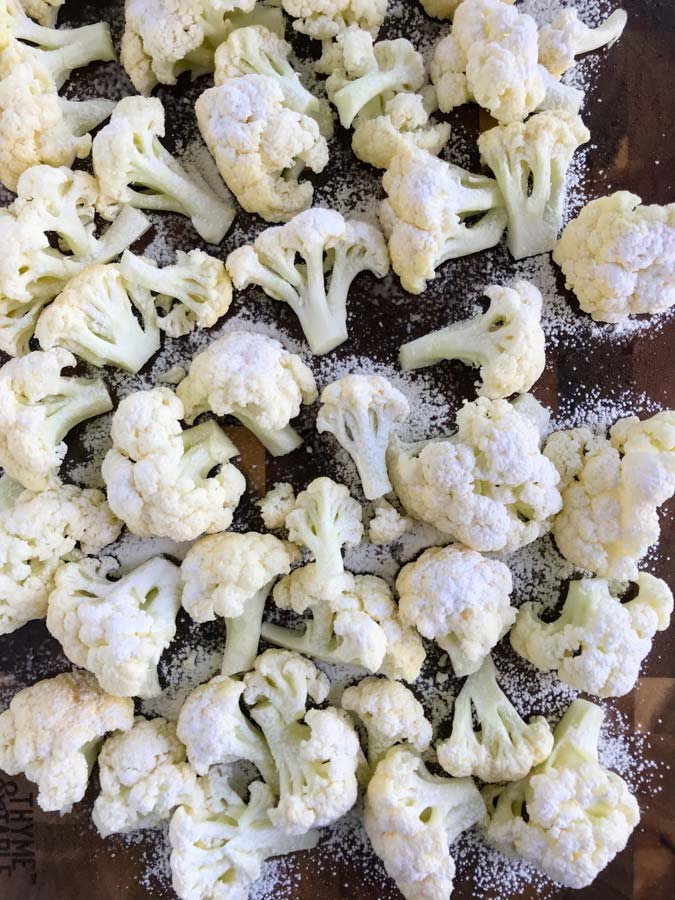 Cauliflower dusted with corn flour on a baking sheet.