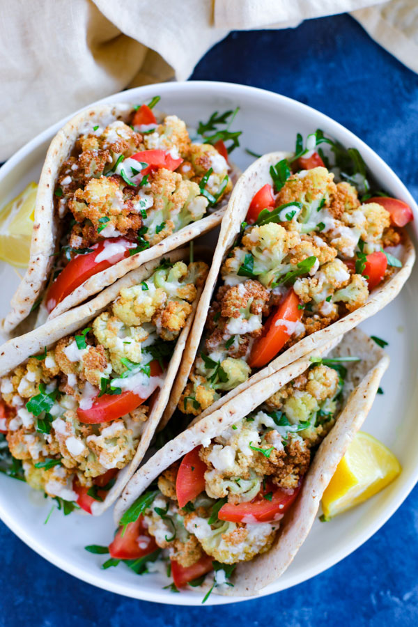 A white plate with vegetarian cauliflower wraps on a blue counter.