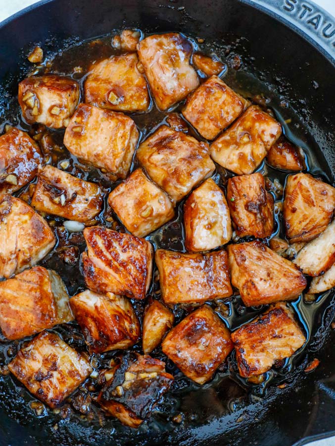 Salmon and teriyaki sauce cooking in a nonstick skillet.