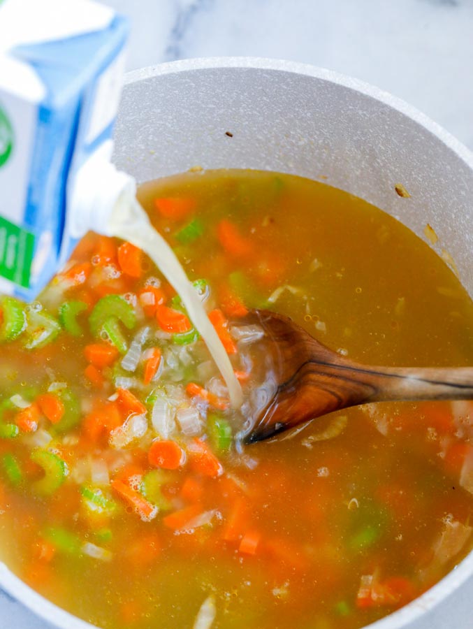 Top down shot of mixing broth into a bowl of diced vegetables.