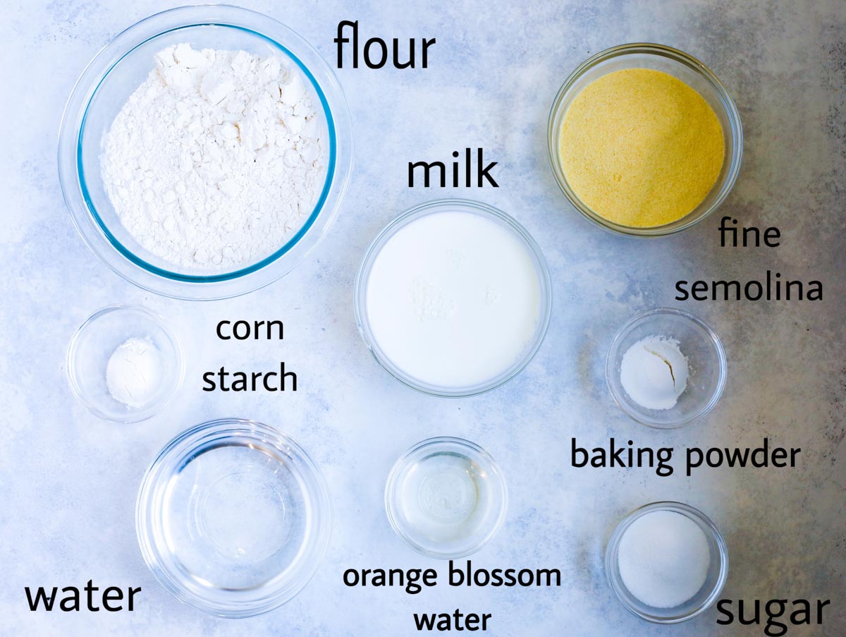 Atayef pancake ingredients laid out on a table. flour, milk, fine semolina, corn starch (optional) baking powder, sugar, water and orange blossom water.